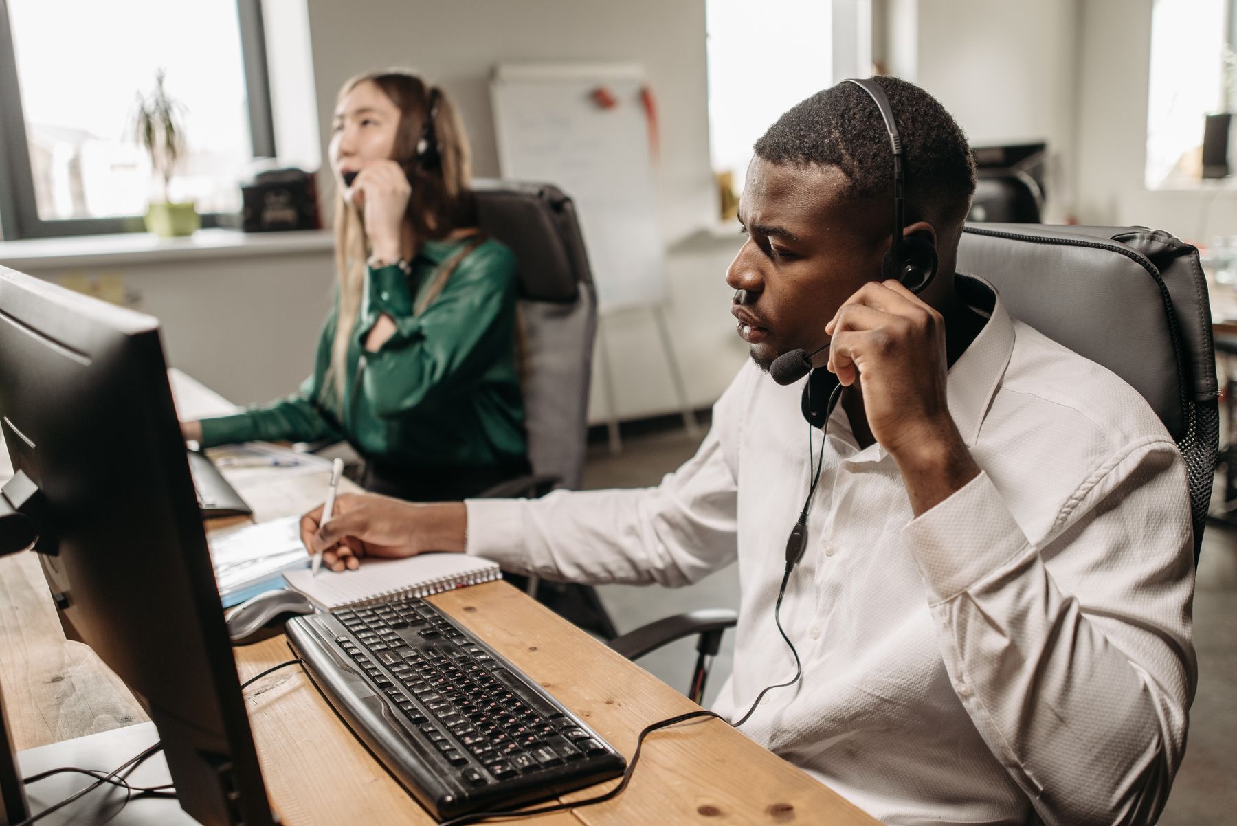 Two professionals helping callers from a shared workspace